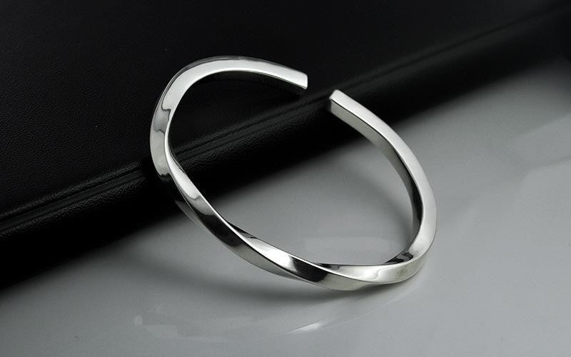 Sleek and polished Luxury Metal Bracelet resting on a reflective surface with a black textured background