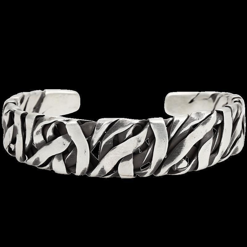 Close-up of a twisted and textured metal cuff styled as a Luxury Metal Bracelet in silver finish against black background