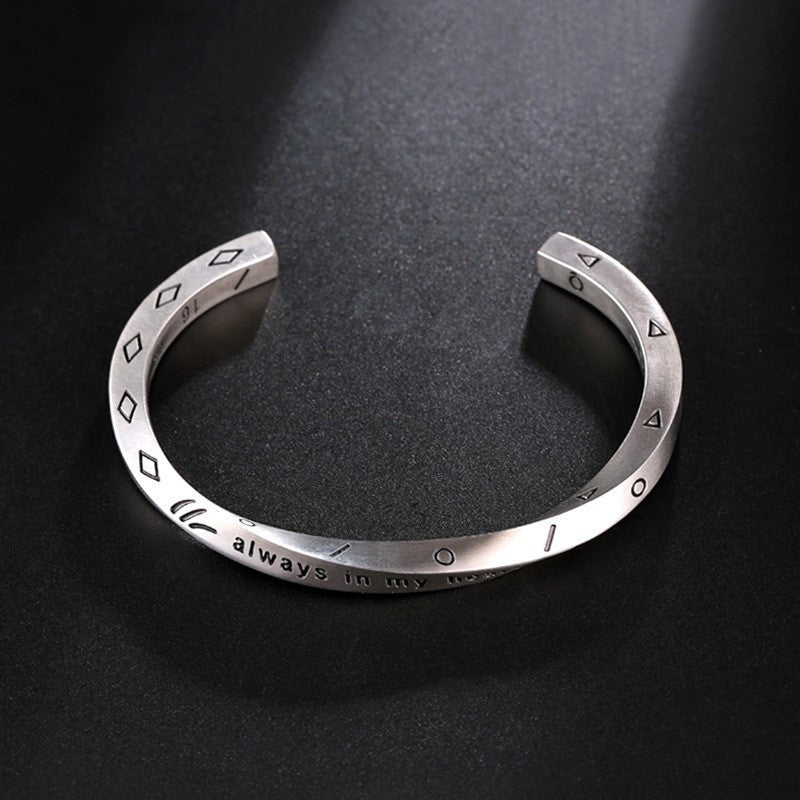 Luxury Metal Bracelet with engraved geometric symbols and inspirational text on a sleek silver band on dark background